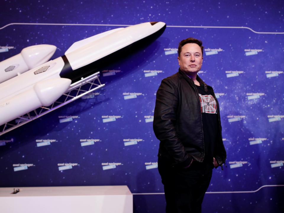 Elon Musk stands next to a replica spaceship