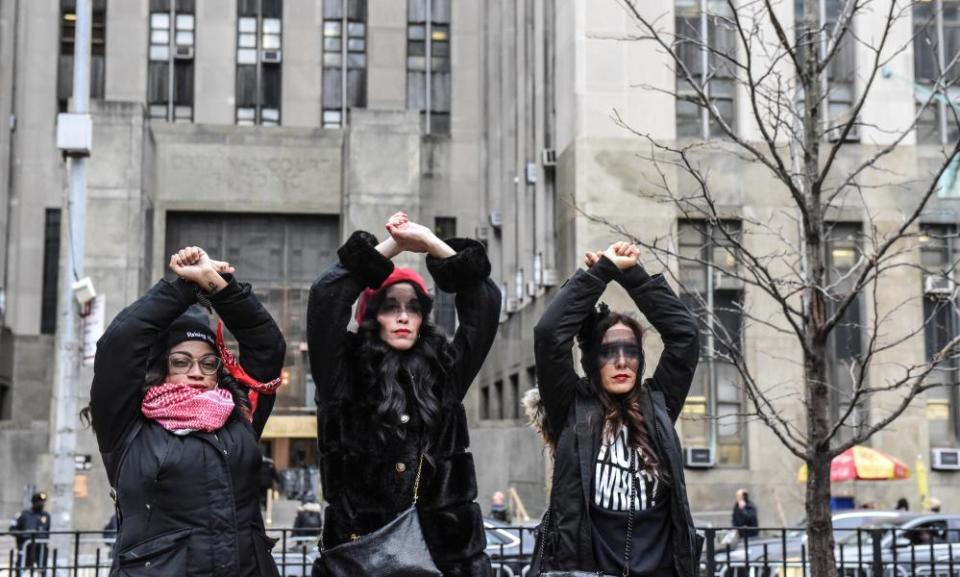 three women in black with raised arms outside courthouse