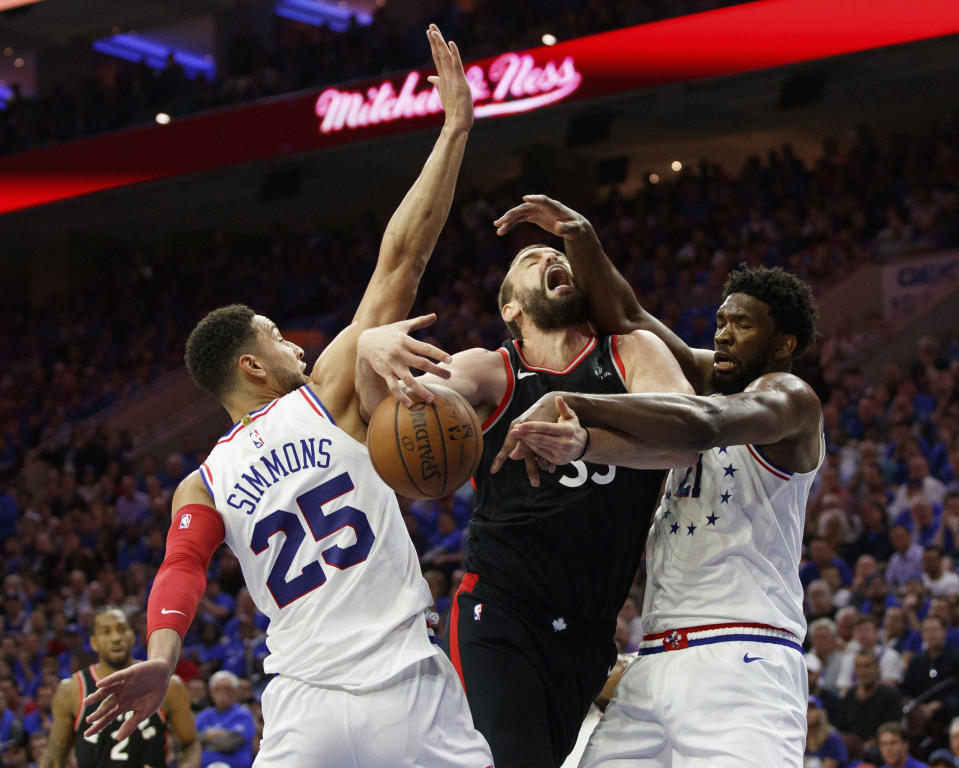 Toronto Raptors' Marc Gasol, center, is fouled by Philadelphia 76ers' Ben Simmons, left, with Joel Embiid, right, also defending during the first half of Game 3 of a second-round NBA basketball playoff series, Thursday, May 2, 2019, in Philadelphia. (AP Photo/Chris Szagola)