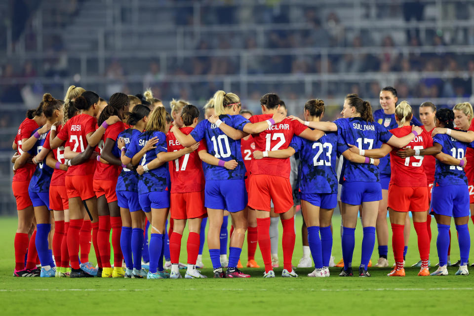 ORLANDO, FLORIDA - FEBRUARY 16: Team Canada and Team United States huddle together before the 2023 SheBelieves Cup game at Exploria Stadium on February 16, 2023 in Orlando, Florida.  (Photo by Mike Ehrmann/Getty Images)