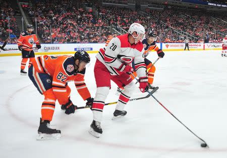 Jan 20, 2019; Edmonton, Alberta, CAN; Edmonton Oilers defenceman Caleb Jones (82) battles for the puck with Carolina Hurricanes center Sebastian Aho (20) during the first period at Rogers Place. Carolina won the game 7-4. Mandatory Credit: Walter Tychnowicz-USA TODAY Sports