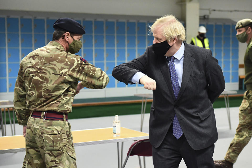 Britain's Prime Minister Boris Johnson elbow bumps a member of the military as he meets troops setting up a vaccination centre in the Castlemilk district of Glasgow, on his one day visit to Scotland, Thursday, Jan. 28, 2021. Johnson is facing accusations that he is not abiding by lockdown rules as he makes a trip to Scotland on Thursday to laud the rapid rollout of coronavirus vaccines across the United Kingdom. (Jeff Mitchell/Pool Photo via AP)