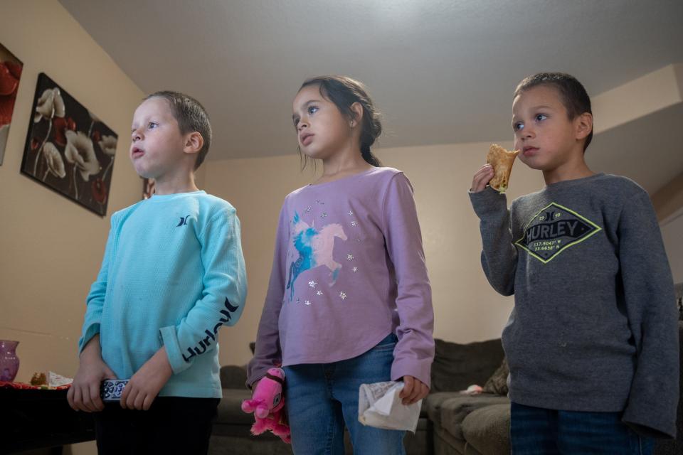Avier, Alvira, and Adriel Arvizo eat tacos and watch television at their temporary home in Avondale, Arizona, on Nov. 18, 2022.