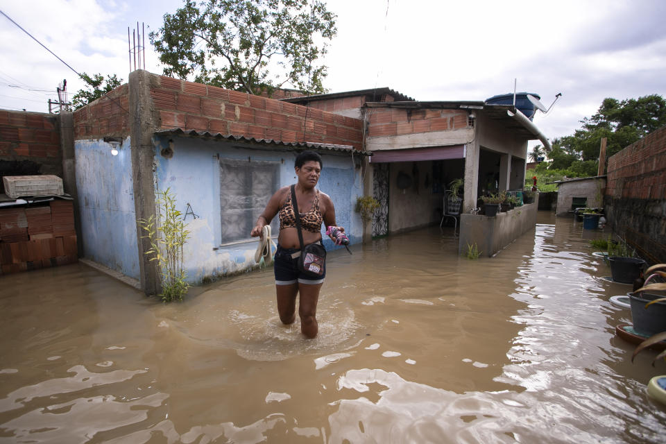 Luciana Carlos Moreira walks outside her flooded home after deadly, heavy rainfall in Duque de Caxias, Brazil, Sunday, Jan. 14, 2024. (AP Photo/Bruna Prado)