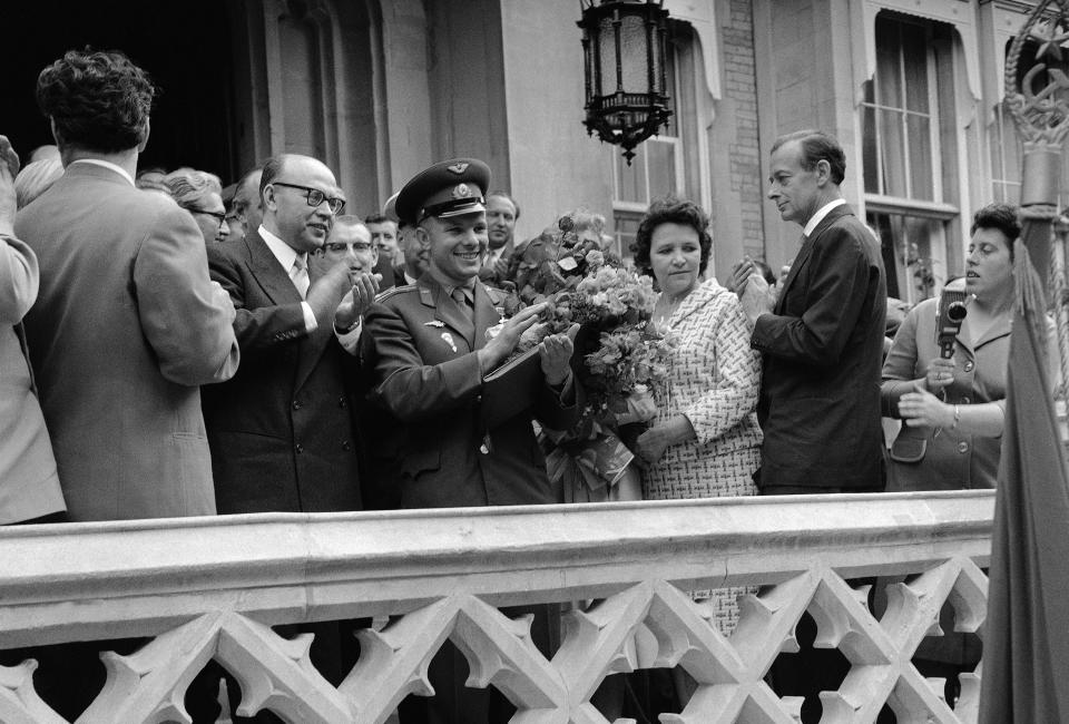 FILE - In this Tuesday, July 11, 1961 file photo, Russian cosmonaut Major Yuri Gagarin, center, with a large bouquet on his arm, applauds at the Russian embassy in London, after his arrival from London Airport.The successful one-orbit flight on April 12, 1961 made the 27-year-old Gagarin a national hero and cemented Soviet supremacy in space until the United States put a man on the moon more than eight years later. (AP Photo/File)