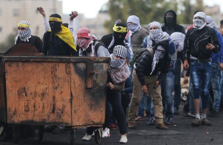 Palestinian protesters take cover during clashes with Israeli troops near the Jewish settlement of Bet El, near the West Bank city of Ramallah October 29, 2015. REUTERS/Mohamad Torokman