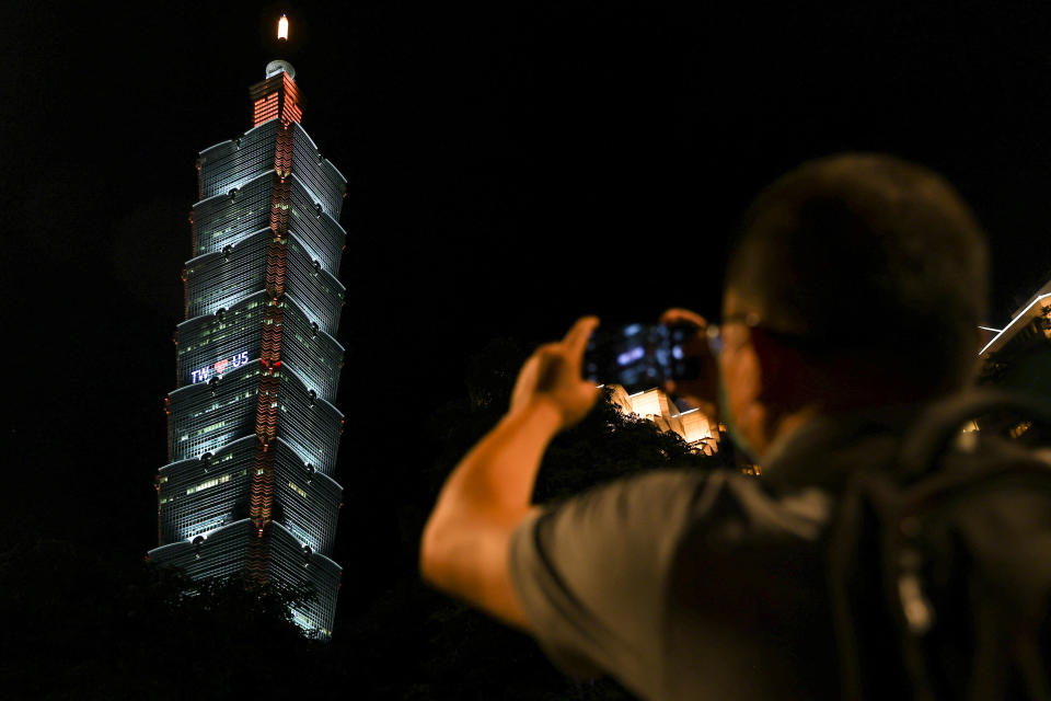 A person takes a picture of a pro-US sign displayed on a tower in Taipei.