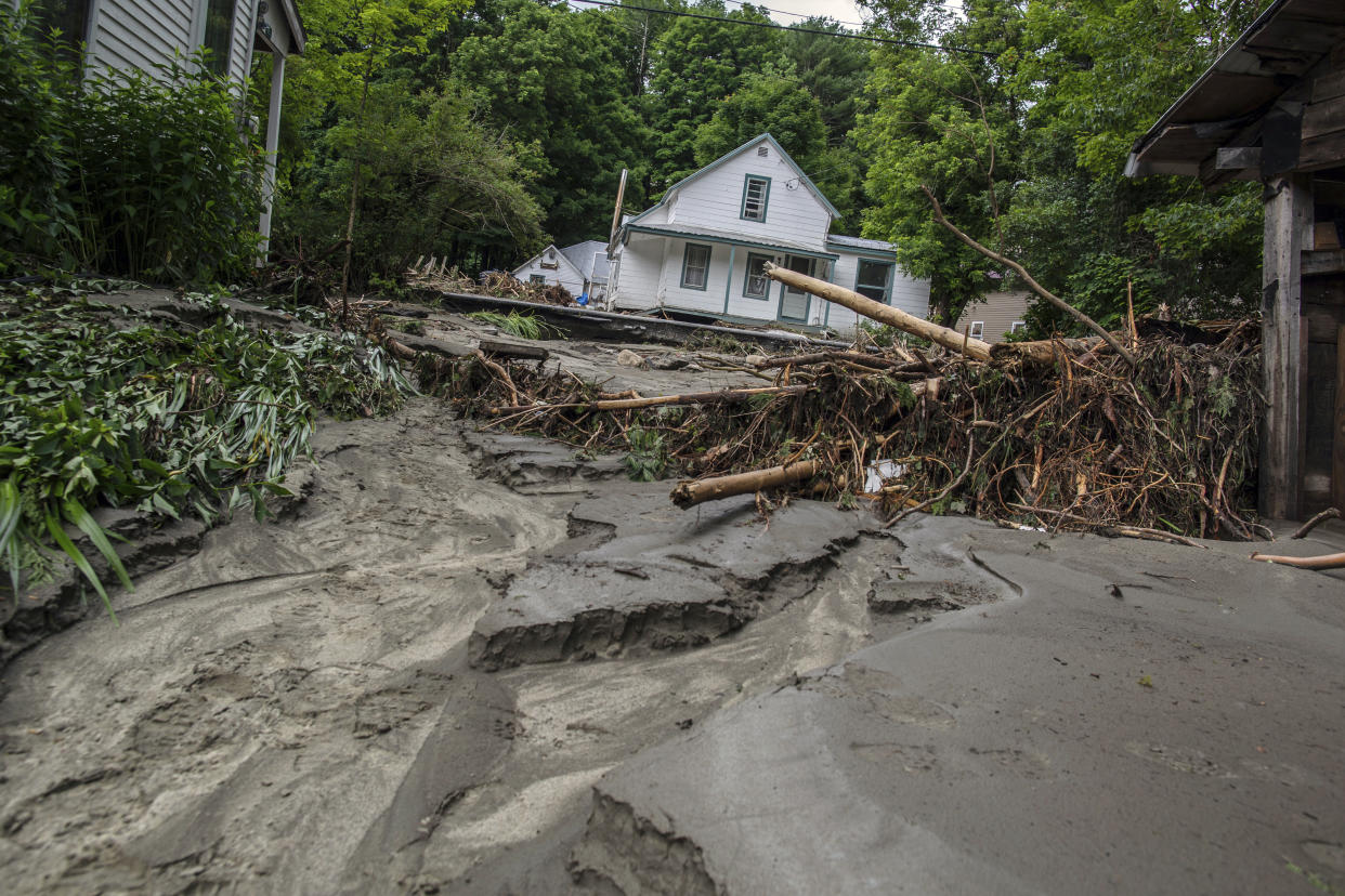 A damaged house surrounded by debris.