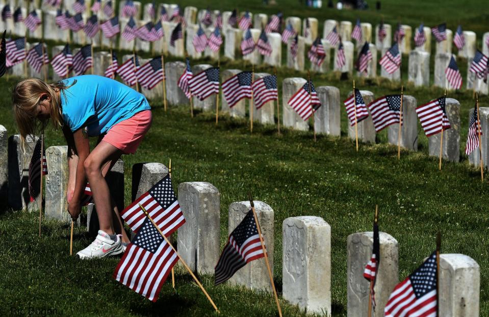 Dorothy Lowe, a fifth grader at Sharpsburg Elementary School, places a flag at a gravestone in Antietam National Cemetery in Sharpsburg on Thursday. The tradition is for fifth graders from the school to place nearly 5,000 of the flags at the stones to commemorate Memorial Day.