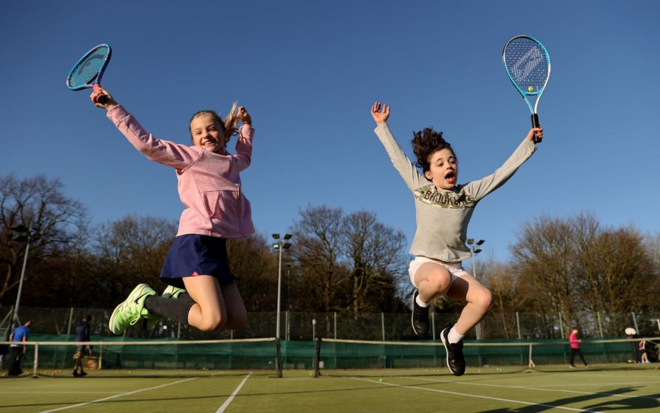 Friends leap with joy at the Sale sports club's tennis courts before their first group tennis coaching session since the lockdown started in early January - Clive Brunskill/Getty Images