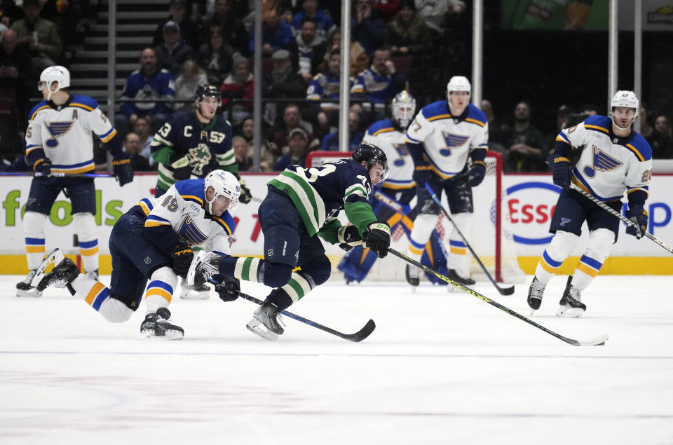 Vancouver Canucks' Quinn Hughes (43) is upended by St. Louis Blues' Ivan Barbashev (49), of Russia, during the second period of an NHL hockey game in Vancouver, British Columbia, Monday, Dec. 19, 2022. (Darryl Dyck/The Canadian Press via AP)