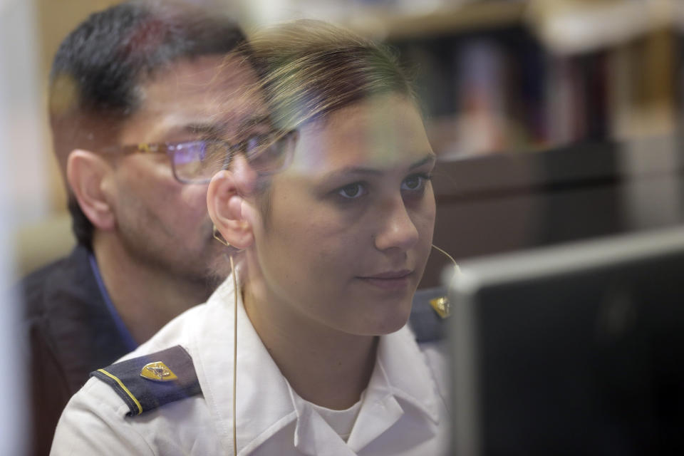 In this file photo from May 2, 2019, visiting scientist Richard DiNinni, reflected in glass, watches as Cadet Cheyenne Quilter works with a virtual reality character named "Ellie" at the U.S. Military Academy at West Point, N.Y. Artificial intelligence is spreading into health care, often as software or a computer program capable of learning from large amounts of data and making predictions to guide care or help patients. (AP Photo/Seth Wenig, File)