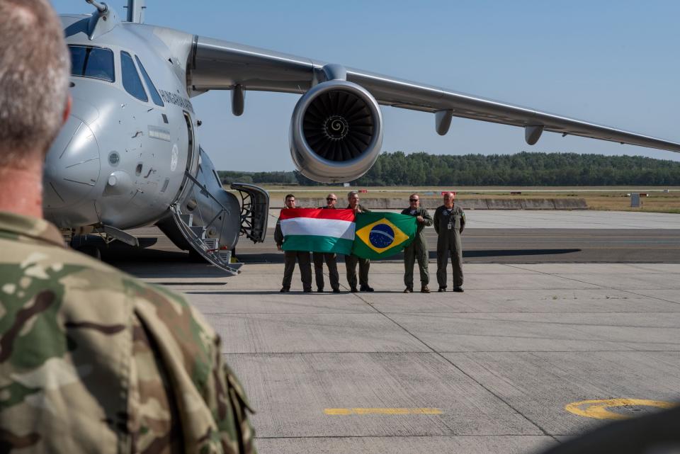 The C-390 being delivery to Hungary with troops holding the Hungarian and Brazilian flags.