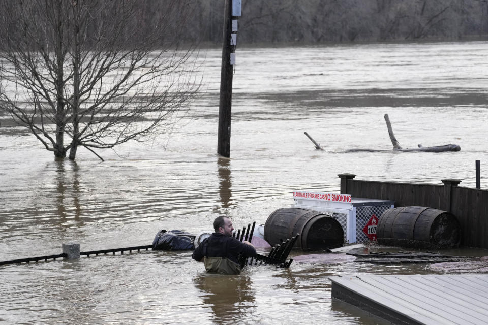 Nathan Sennett wades to retrieve furniture in hip-deep water on the patio of the Quarry Tap Room, Tuesday, Dec. 19, 2023, in Hallowell, Maine. Waters continue to rise in the Kennebec River following Monday's severe storm. (AP Photo/Robert F. Bukaty)