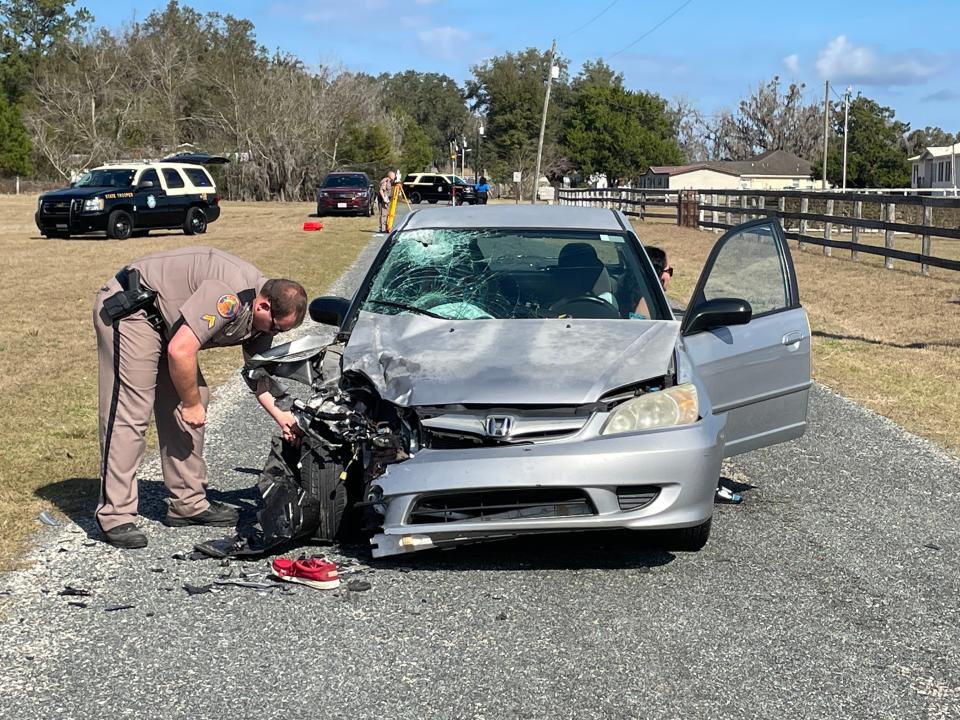 An FHP trooper inspects the Honda Civic that was involved in a two-vehicle crash Tuesday in Flemington that claimed the life of James Wilkerson, a North Marion High School student.