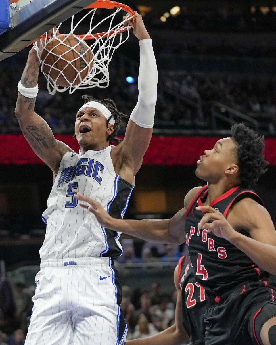 Orlando Magic's Paolo Banchero (5) dunks next to Toronto Raptors' Scottie Barnes during the second half of an NBA basketball game Friday, Dec. 9, 2022, in Orlando, Fla. (AP Photo/John Raoux)