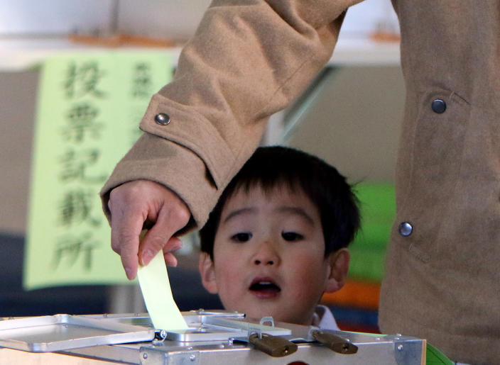 A boy watches as his father casts a vote in Japan's general election at a polling station in Tokyo on December 14, 2014 (AFP Photo/Yoshikazu Tsuno)