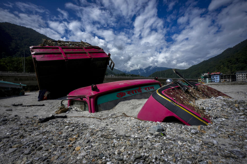 Vehicles lie submerged in mud in the flood affected area along the Teesta river in Rongpo, east Sikkim, India, Sunday, Oct. 8. 2023. Rescuers continued to dig through slushy debris and ice-cold water in a hunt for survivors after a glacial lake burst through a dam in India’s Himalayan northeast, shortly after midnight Wednesday, washing away houses and bridges and forcing thousands to flee. (AP Photo/Anupam Nath)