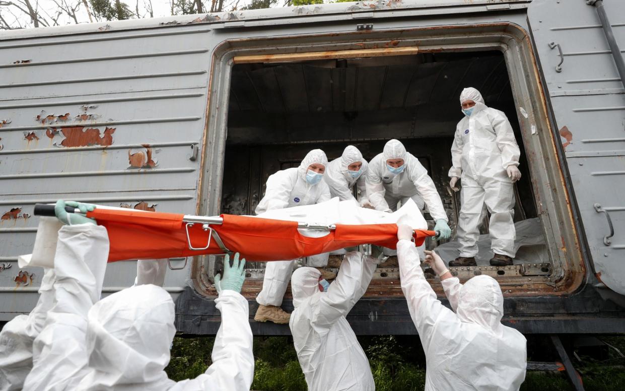 Ukrainian servicemen load a refrigerated rail car with bodies of Russian soldiers - VALENTYN OGIRENKO /REUTERS