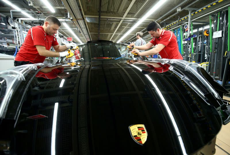 FILE PHOTO: Employees of German car manufacturer Porsche install the windshield of a Porsche 911 at the Porsche factory in Stuttgart-Zuffenhausen