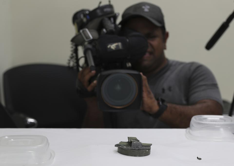 A cameraman takes footage of a magnet the U.S. Navy says came from a limpet mine that didn't explode on a Japanese-owned oil tanker at a 5th Fleet base, during a trip organized by the Navy for journalists, near Fujairah, United Arab Emirates, Wednesday, June 19, 2019. Cmdr. Sean Kido of the U.S. Navy's 5th Fleet said Wednesday that the limpet mine used on a Japanese-owned oil tanker last week "bears a striking resemblance" to similar Iranian mines. (AP Photo/Kamran Jebreili)