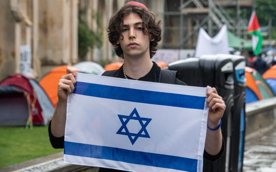 Ari Vladimir, 19, a Jewish first-year History student at Cambridge, raises an Israeli flag near the encampment