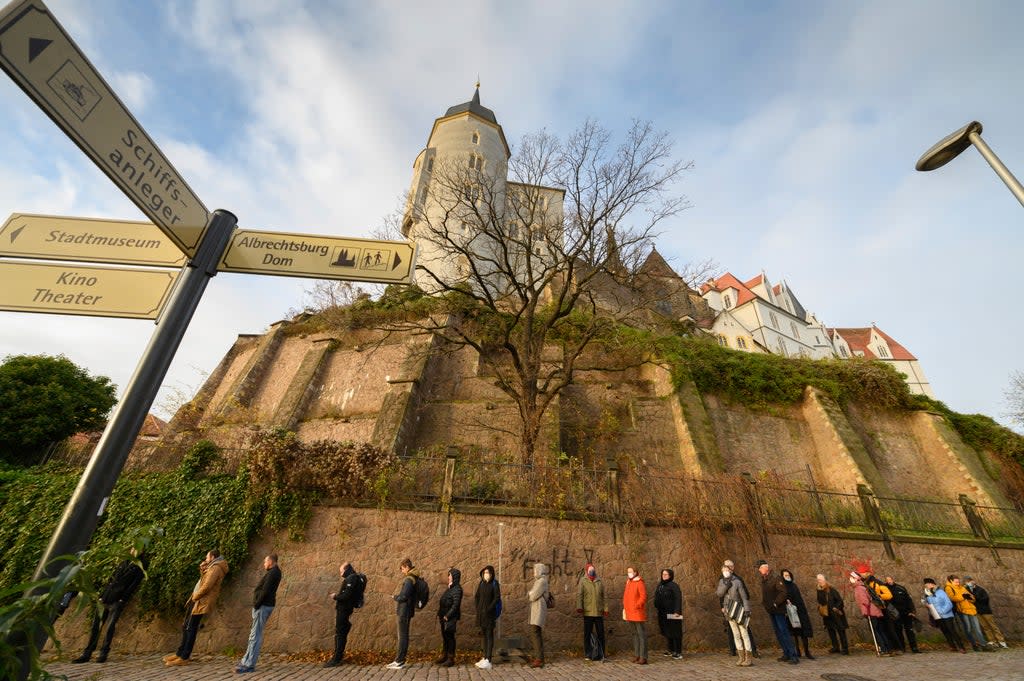 People wait in line for a Covid vaccine below the Albrechtsburg castle in Meissen, Germany (AP)