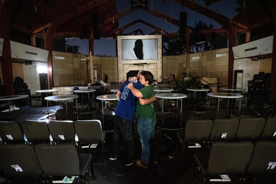 Matt Younger, right, a pastor at Northway Church, embraces facilities associate Robert Lusk in their church's severely damaged sanctuary after a tornado tore through North Dallas.