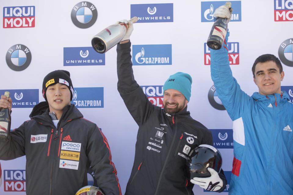 Second placed Yun Sung-bin from South Korea, winner Martins Dukurs from Latvia and third placed Nikita Tregybov from Russia celebrate after the men's skeleton World Cup in St. Moritz, Switzerland, Friday, Jan. 20, 2017. (Urs Flueeler/Keystone via AP)