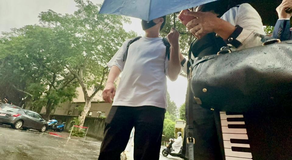 實習律師鄭兆宇(白衣黑褲)拿雨傘擋臉。侯柏青攝