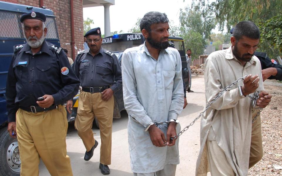 Pakistani police officers escort Farman Ali, right, and Arif Ali, two brothers suspected of cannibalism to a local court in Sargodha, Pakistan, Tuesday, April 15, 2014. Police raided their house in central Pakistan Monday morning after neighbors complained of a horrible stench. Police officer Zafar Iqba said the men were previously jailed for two years on charges of digging up bodies, cooking and eating them in 2011. (AP Photo/M.I. Haq)