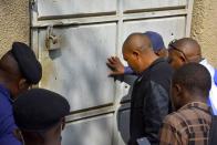 Congolese security officers look at a broken door at the Kangbayi central prison in Beni