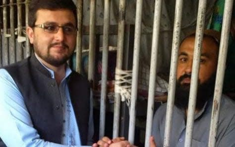 Muslim Afghan (left) shaking hands with a fellow prisoner in Kabul's Pul-e-Charkhi prison