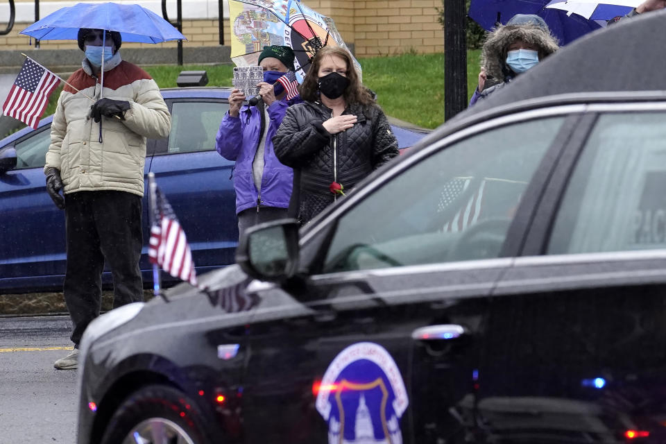 A woman, center, places her hand on her chest as a hearse carrying the coffin of the late U.S. Capitol Police officer William "Billy" Evans, right, drives though downtown Adams, Mass., following a funeral Mass for Evans, Thursday, April 15, 2021. Evans, a member of the U.S. Capitol Police, was killed on Friday, April 2, when a driver slammed his car into a checkpoint he was guarding at the Capitol. (AP Photo/Steven Senne)