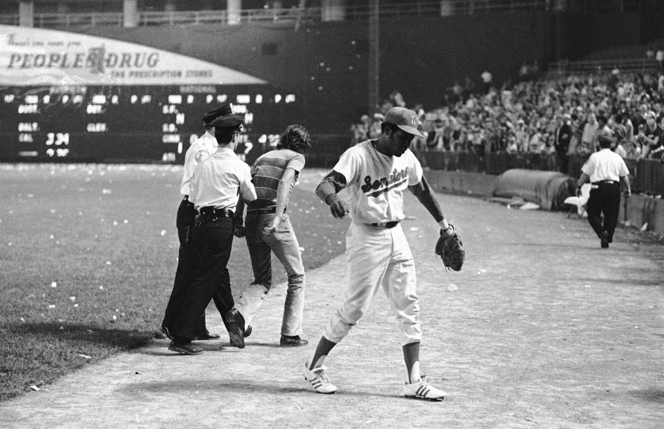 FILE - Dave Nelson of the Washington Senators makes his way toward the dugout as fans begin to storm the field in Washington, Oct. 1, 1971. The Senators forfeited the game to the Yankees due to fan actions. From their beginnings as a hastily assembled replacement team for the nation’s capital in 1961, through a whole lot of losing seasons and one excruciatingly close-but-no-cigar call, the Senators II-turned-Rangers have labored longer than any franchise in America’s four major sports leagues without a championship on their resume. (AP Photo/Jim Palmer, File)