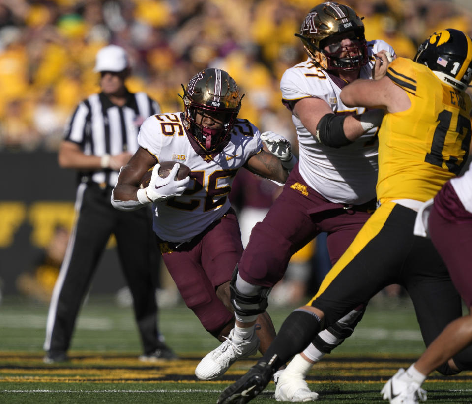 Minnesota offensive lineman Quinn Carroll (77) blocks Iowa defensive end Joe Evans (13) as Minnesota running back Zach Evans (26) runs the ball during the first half of an NCAA college football game, Saturday, Oct. 21, 2023, in Iowa City, Iowa. (AP Photo/Matthew Putney)