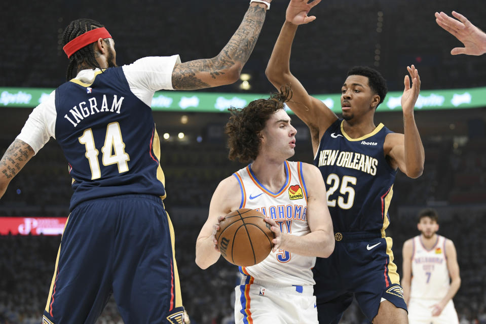 Oklahoma City Thunder guard Josh Giddey, middle, tries to pass around New Orleans Pelicans forward Brandon Ingram (14) and guard Trey Murphy III (25) in the first half of Game 1 of an NBA basketball first-round playoff series, Sunday, April 21, 2024, in Oklahoma City. (AP Photo/Kyle Phillips)