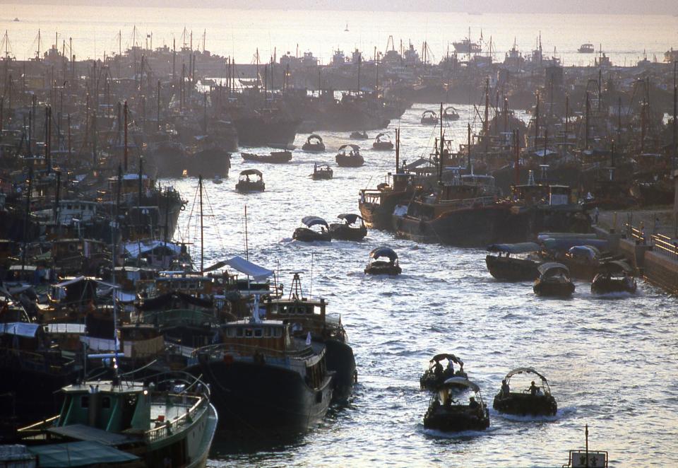 Sampans and junk boats cruise in the water in Aberdeen Harbor.