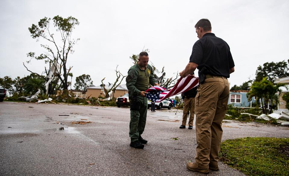 Lee County Sheriff Carmine Marceno folds a  American flag after a flag pole was damaged in the Century 21 Mobile Home Park in a tornado in the Iona area in Fort Myers  on Sunday Jan, 16, 2022.  