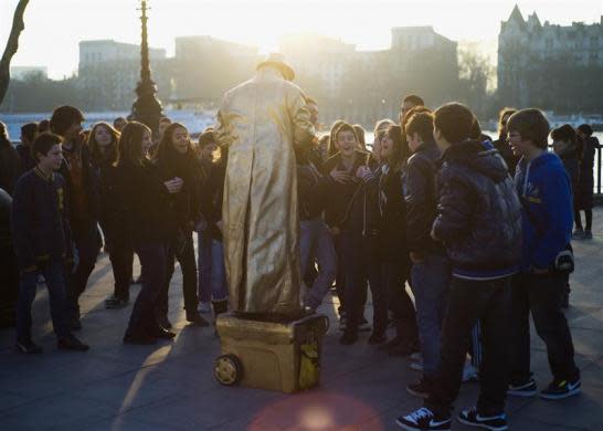 A performance artist performs to tourists along the south bank on the River Thames in London March 13, 2012.