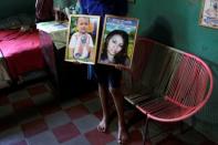 Brother of late Honduran migrant Herrera holds framed pictures of his sister and nephew at her home in El Limon