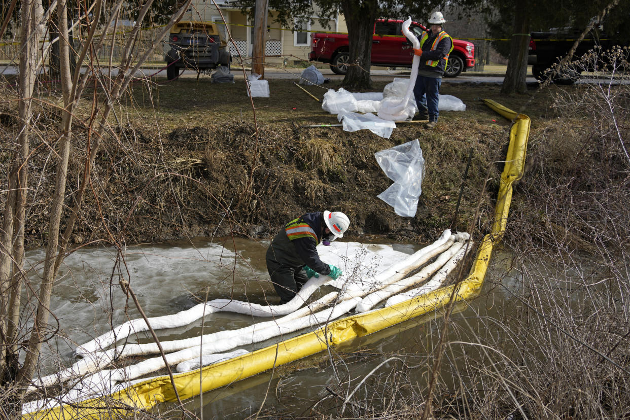 Workers place booms in a stream 