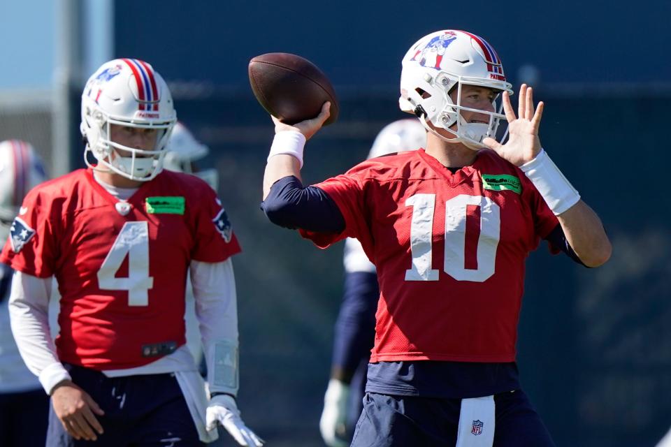 New England Patriots quarterback Mac Jones (10) winds up to pass as quarterback Bailey Zappe (4) looks on during an NFL football practice, Thursday, Oct. 6, 2022, in Foxborough, Mass. (AP Photo/Steven Senne)