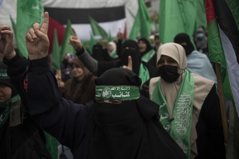 A Palestinian woman with a green head band with Arabic waiting that reads "Qassam Brigades" chants Islamic slogans as she attends a rally marking the 34th anniversary of Hamas movement's founding, in Gaza City, Friday, Dec. 17, 2021. Gaza’s Hamas rulers collect millions of dollars a month in taxes and customs at a crossing on the Egyptian border – providing a valuable source of income that helps it sustain a government and powerful armed wing. After surviving four wars and a nearly 15-year blockade, Hamas has become more resilient and Israel has been forced to accept that its sworn enemy is here to stay. (AP Photo/ Khalil Hamra)