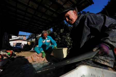 Men crash the glass as they clean debris in the aftermath of Typhoon Hagibis in Yanagawamachi district, Date City