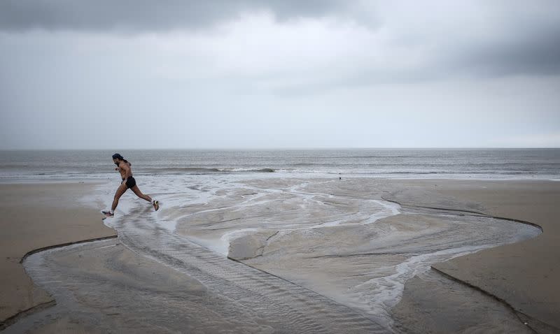 A man runs on a beach along the Arabian Sea against the backdrop of monsoon clouds in Mumbai August 25, 2014. REUTERS/Danish Siddiqui