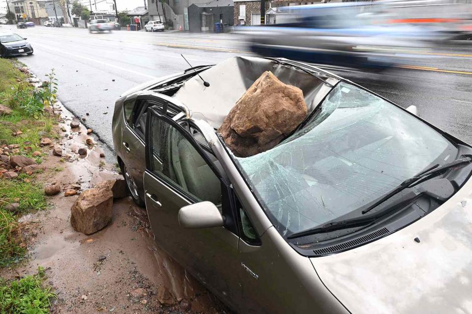 Wally Skalij/Los Angeles Times via Getty A boulder crashed on top of a parked car along the Pacific Coast Highway in Malibu, California