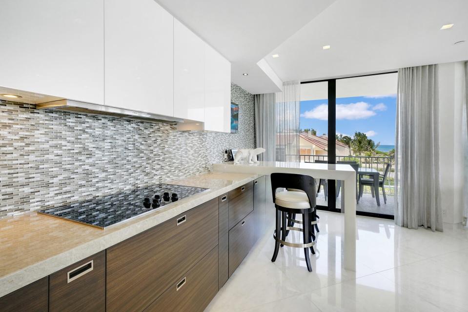 With a glass-tiled backsplash, the kitchen has a breakfast area with a built-in bar-height table.