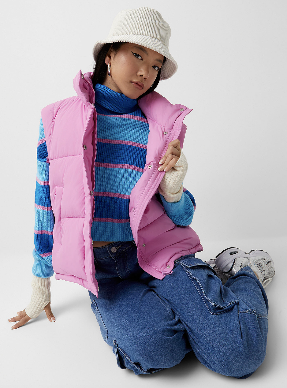 model in blue jeans, blue striped shirt and pink Solid Puffer Vest (photo via Simons)