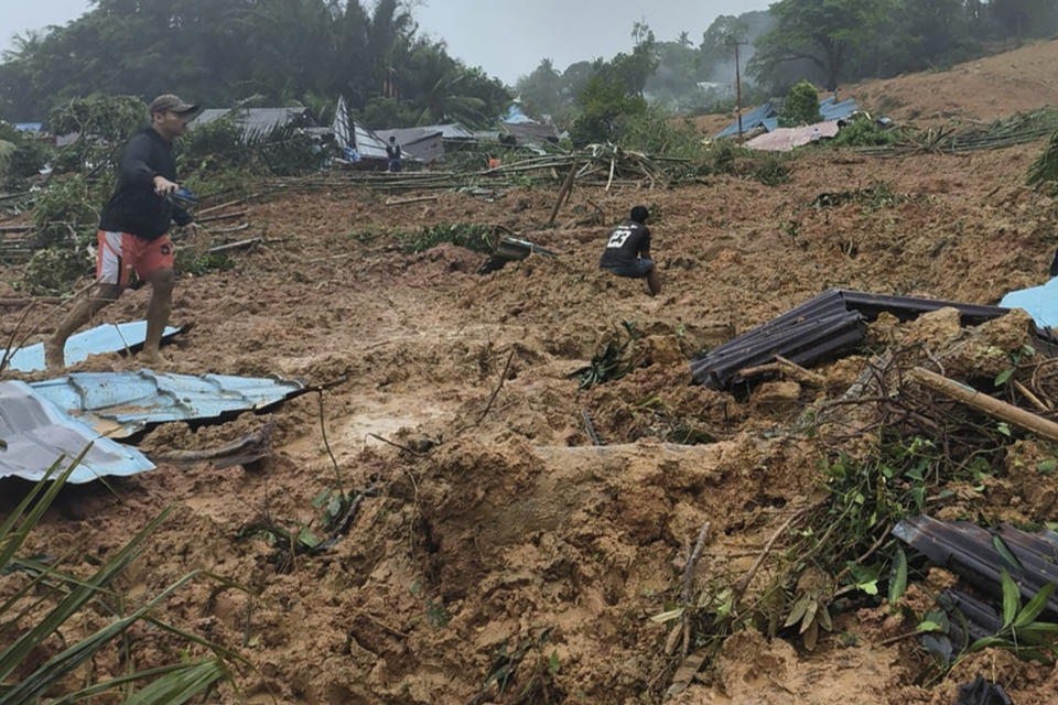 In this frame grab made from video released by Indonesia's National Disaster Management Agency (BNPB), people inpspect the site where a landslide hit a village on Serasan Island, Natuna regency, Indonesia, on Monday, March 6, 2023. The landslide caused by torrential rain killed a number of people and left dozens of others missing on the remote island, disaster officials said. (BNPB via AP)